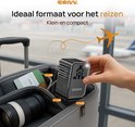 DRIVV. reisadapter in de hand, naast een koffer op de luchthaven. Afmetingen 75x55x53mm. Ideaal voor reizen, klein en compact.