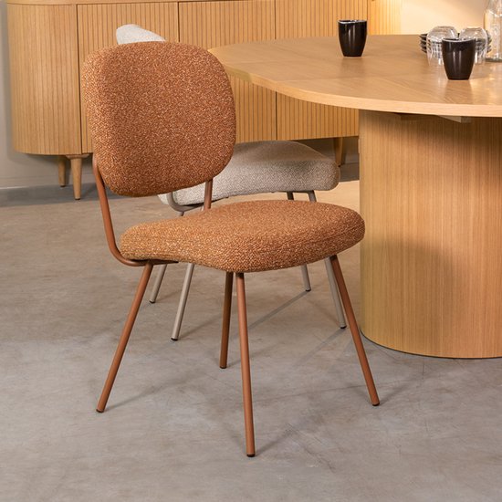 Oranje eetkamerstoel met een koraal metalen frame, naast een houten eettafel.