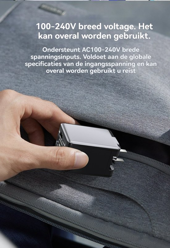 Hand plaatst een zwarte compacte oplader in een grijze tas.