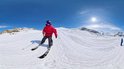 Skiër in rood jack skiet op besneeuwde piste met blauwe lucht.