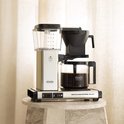 Zilverkleurige Moccamaster Select koffiezetapparaat op marmeren plateau met glazen kan en koffie.