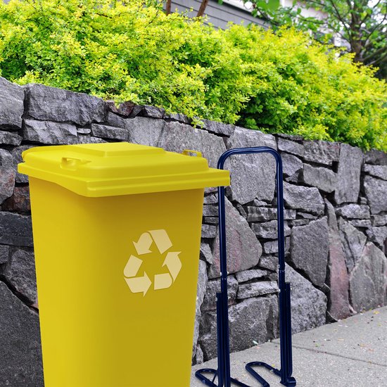 Blauwe metalen afvalpers naast een gele kliko met een recycling symbool, op een stenen muur en stoep.