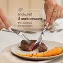 Een vrouw snijdt een biefstuk met een gekarteld steakmes van de Deleca Amor bestekset.