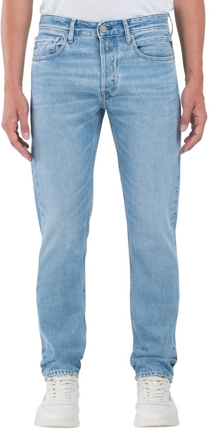 Homme en jean Replay bleu clair, le devant est visible. Le pantalon a une étiquette Replay en cuir au dos.