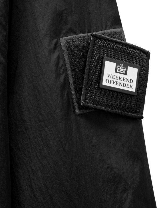 Zwarte jas met een vierkant patch met het Weekend Offender logo op de linker mouw.