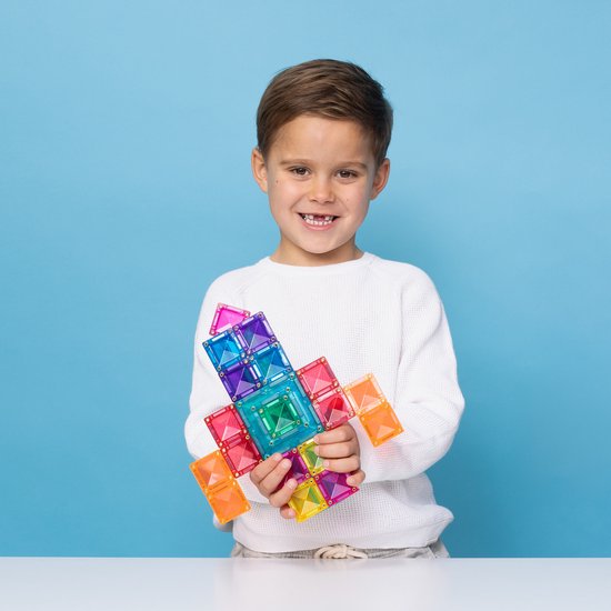 Jongen met een witte trui die een gekleurd, magnetisch Connetix speelgoed zwaard vasthoudt.
