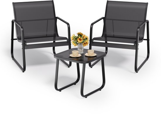 Twee zwarte lounge stoelen met een bijzettafel, versierd met bloemen en kopjes koffie.