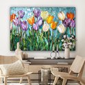 Mozaïek van kleurrijke tulpen boven een dressoir met vazen en een kandelaar in een woonkamer.