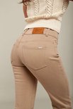 Detail van de achterkant van beige jeans met een bruin leren label en een zak.
