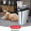 Zilverkleurige voedselcontainer op wieltjes, naast een slapende collie en andere voercontainers.