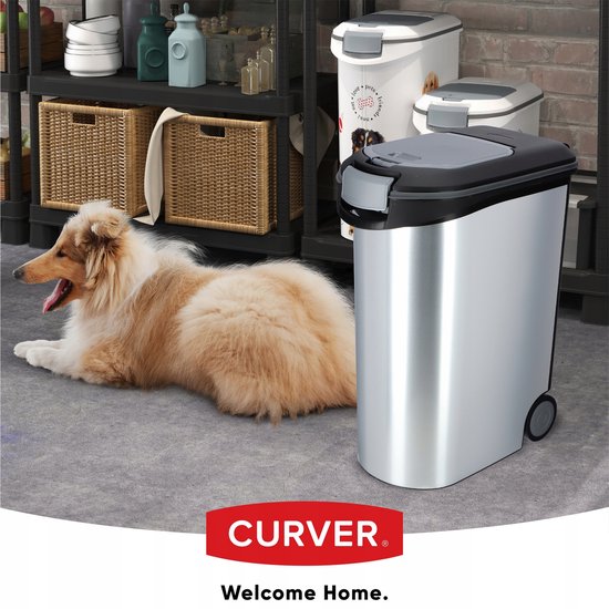 Zilverkleurige voedselcontainer op wieltjes, naast een slapende collie en andere voercontainers.