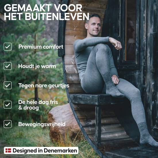 Man in donkergrijs merino thermoshirt en broek, zittend op een houten bankje buiten. "Gemaakt voor het buitenleven", "Premium comfort", "Houdt je warm", "Tegen nare geurtjes", "De hele dag fris & droog", "Bewegingsvrijheid". "Designed in Denemarken".