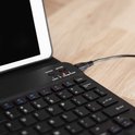Close-up van een zwart toetsenbord met een aangesloten micro-USB kabel.