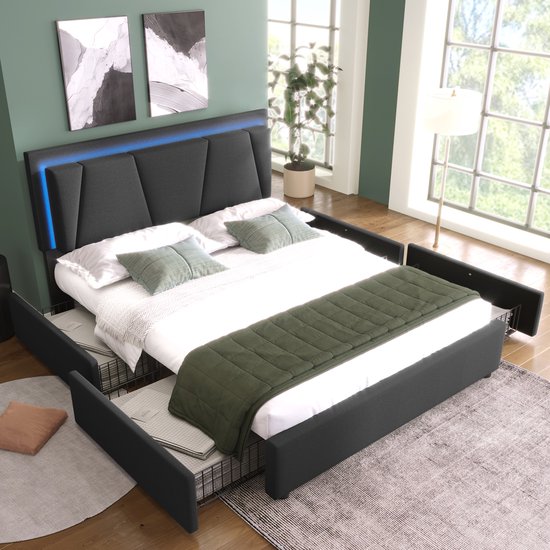 Gedrapeerd donkergrijs bed met kussens, deken en open opberglades, met planten en kunst aan de muur.