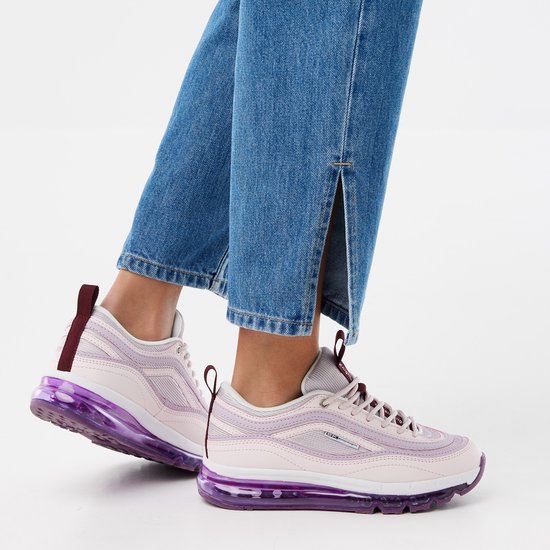 Een vrouw draagt roze sneakers met paarse luchtdemping en jeans met splitjes.