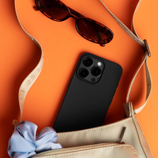Coque de téléphone noire dans un sac beige avec des lunettes de soleil et un chouchou bleu.