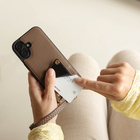 Mains insérant une carte bancaire dans le porte-cartes d'un étui de téléphone marron texturé.