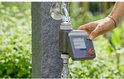 Hand die een Gardena besproeiingscomputer instelt bij een waterkraan.
