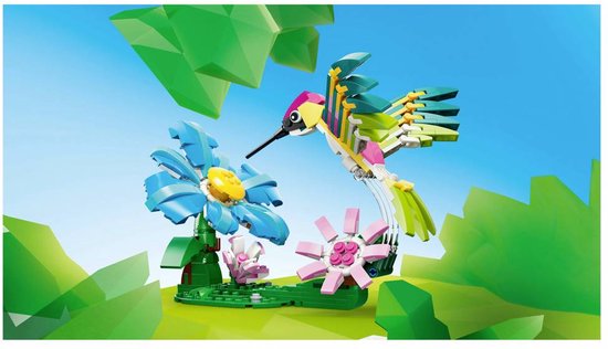 Colibri LEGO coloré volant dans les airs près d'une grande fleur bleue et de deux petites fleurs roses.