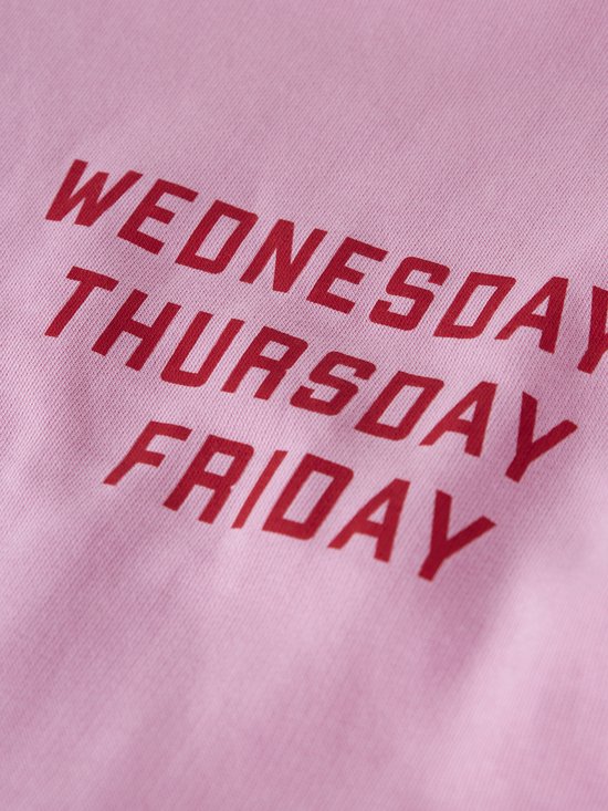Close-up van roze stof met de rode tekst 'WEDNESDAY THURSDAY FRIDAY'.