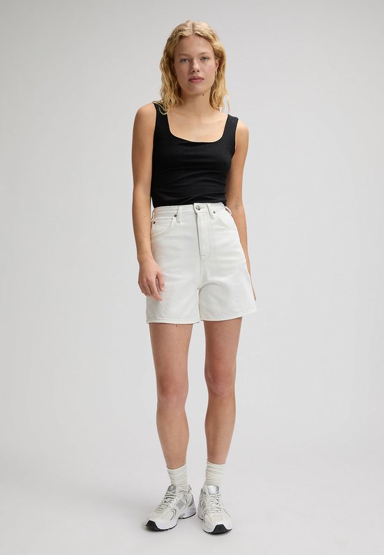Model staat in een witte spijkerbroekshort met wijde pijpen en een zwarte tanktop.