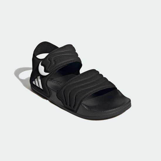Zwarte Adidas Adilette kindersandaal, zijaanzicht met golvend patroon en drievoudig wit logo.