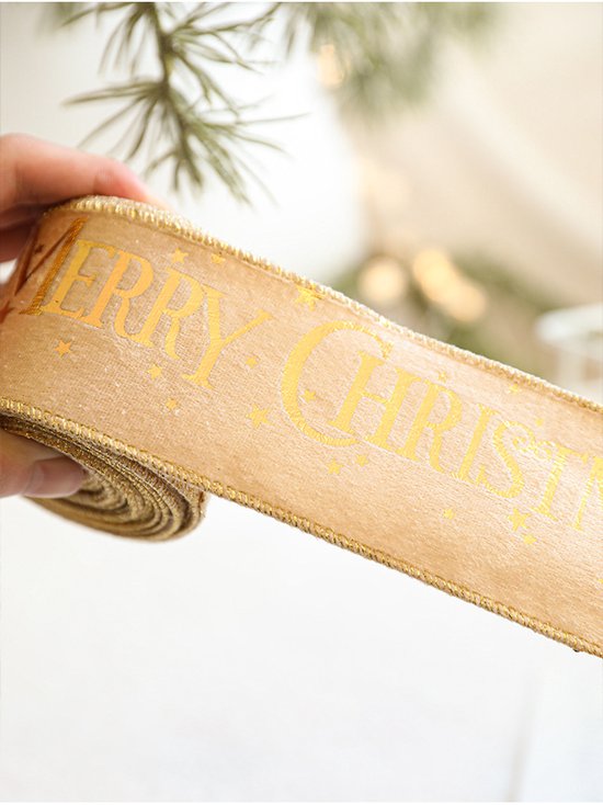 Gouden kerstlint met glanzende 'Merry Christmas'-tekst en kleine sterren, vastgehouden in een hand.