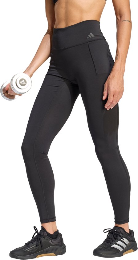 Dames zwarte, nauwsluitende, lange sportlegging met zakken, gedragen door een model met een dumbbell.