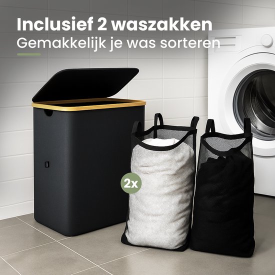 Zwarte wasmand met deksel en bamboe frame, met twee waszakken ernaast in een badkamer.