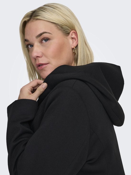 Close-up van een vrouw met blonde haren, die een zwarte jas met capuchon draagt.