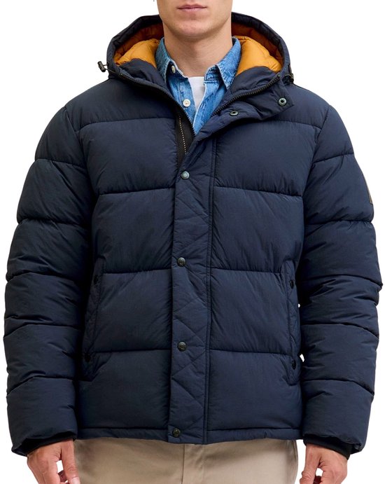 Donkerblauwe pufferjack met capuchon, gele voering, gedragen door een man met spijkerblouse.