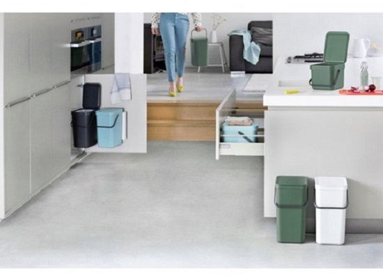 Une cuisine avec différentes poubelles Brabantia en gris foncé, bleu, vert et blanc.