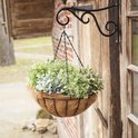 Hangende bloempot met kettingen aan een houten schuur. Gevuld met verschillende groene planten.