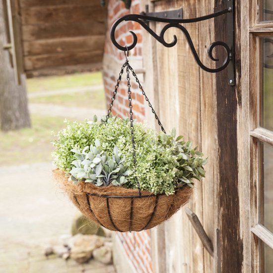 Hangende bloempot met kettingen aan een houten schuur. Gevuld met verschillende groene planten.
