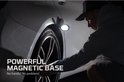 Man met pet kijkt naar een auto, terwijl een Nebo werklamp met magnetische voet aan de auto is bevestigd.