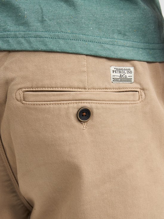 Achterzak van een beige chino short met een knoop en Petrol Industries label.