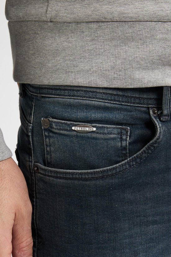 Close-up van de voorkant van een donkerblauwe jeans met Petrol Industries logo.