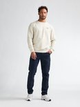 Man draagt een beige sweater en donkerblauwe cargobroek met opgestikte zakken.