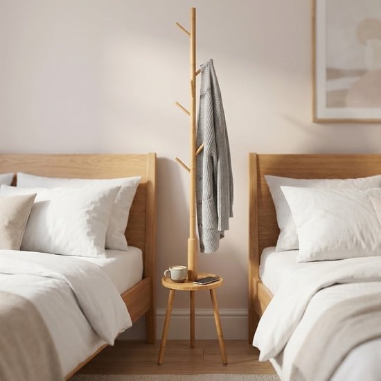 Houten kapstok met een grijze trui, staand tussen twee bedden in een slaapkamer.