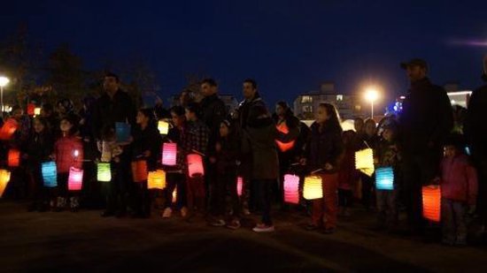 Groep mensen in het donker met kleurrijke verlichte lampionnen tijdens een optocht.