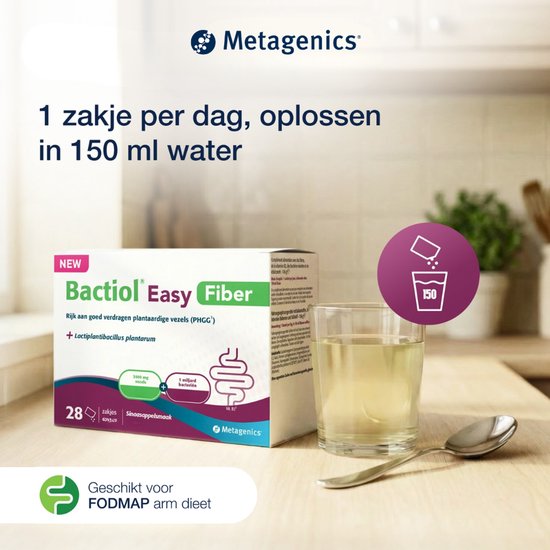 Bactiol Easy Fiber, 28 zakjes sinaasappelsmaak, opgelost in een glas water met een lepel. Achtergrond is een keuken met planten.