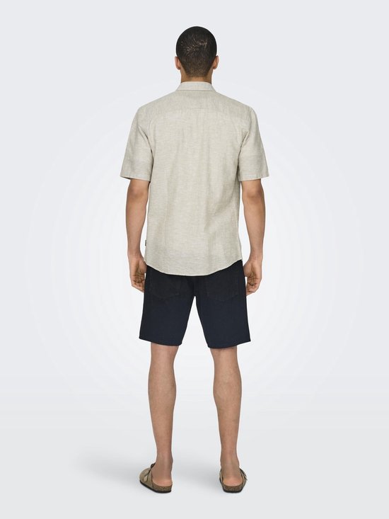 Achterkant van een beige linnenmix overhemd met korte mouwen, gedragen met zwarte shorts.