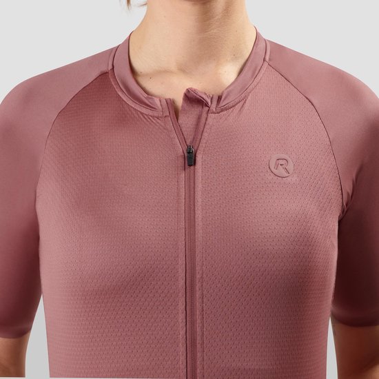 Detail van de ritssluiting en het reliëflogo op de borst van een roze damesfietsshirt.