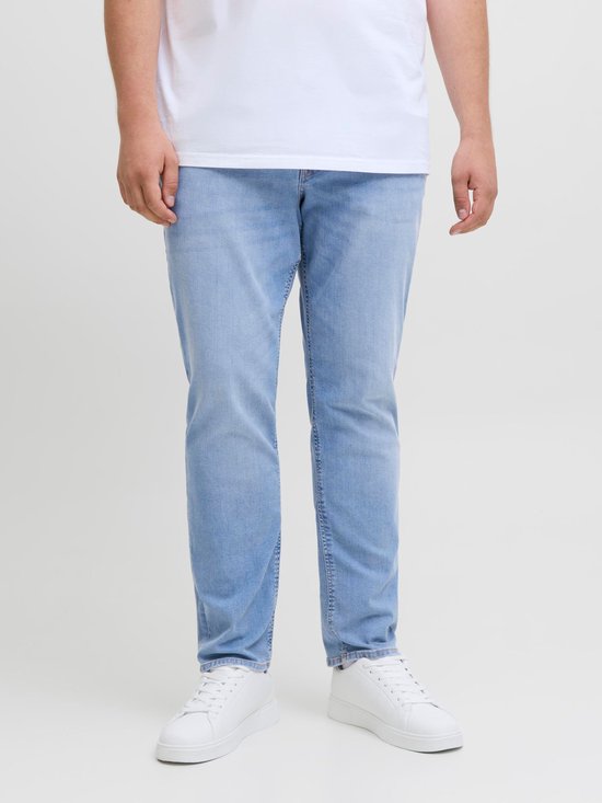 Man draagt een witte T-shirt en een lichtblauwe spijkerbroek, van voren gezien.