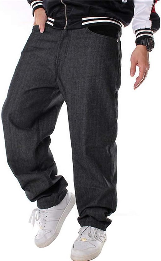 Pantalon en denim noir, ample, coupe droite. Porté avec un blouson bombardier et des baskets blanches.