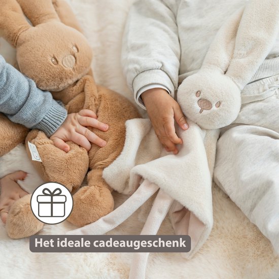 Een baby houdt een crèmekleurig konijnen knuffeldoekje vast. Ideaal als cadeau.