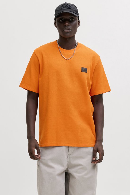 Man met oranje wafel t-shirt met Jack & Jones logo, zilveren ketting en zwarte baseballpet.