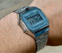 Zilverkleurig Casio horloge met blauwgroen digitaal display, gedragen om een pols.