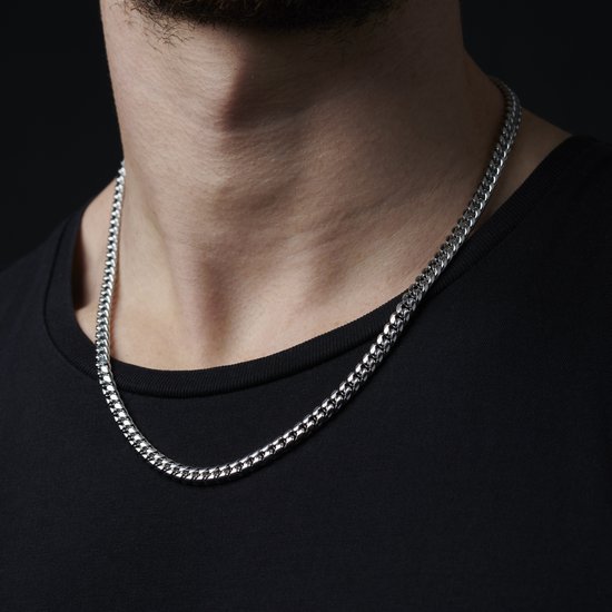 Een man met een zwarte t-shirt draagt een zilverkleurige schakelketting.