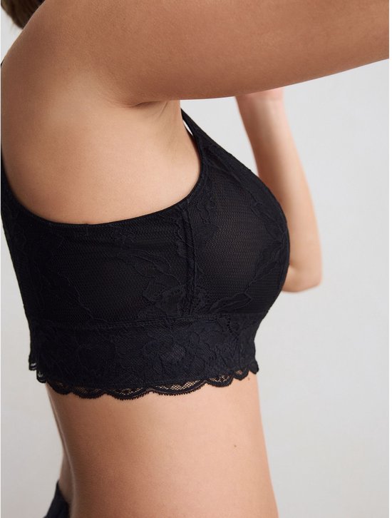 Zij-aanzicht van een model die een zwarte kanten bralette draagt.